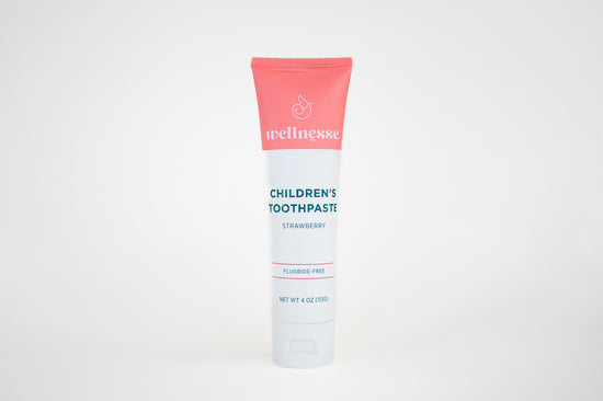 Strawberry fluoride free toothpaste for sensitive teeth in a children's Wellnesse tube with clean design on white background