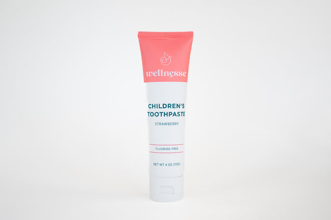 Strawberry fluoride free toothpaste for sensitive teeth in a children's Wellnesse tube with clean design on white background