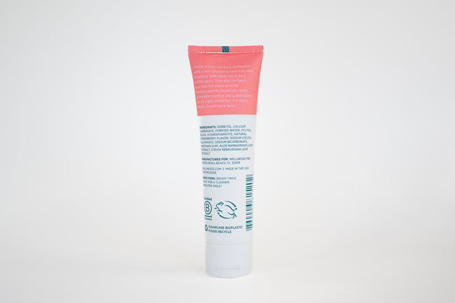 Strawberry fluoride free toothpaste for sensitive teeth with hydroxyapatite and soothing aloe, showing ingredients and benefits on tube back
