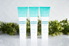 Organic whitening toothpaste trio in Wellnesse fluoride-free fresh mint formula, displayed with green foliage on a tiled surface.