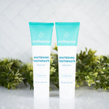 Fluoride free whitening toothpaste twin pack from Wellnesse with fresh mint flavor, displayed against greenery on a tiled background.