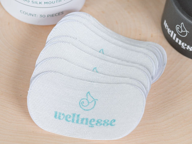 Mouth tape and containers on a wooden surface with 'wellness' branding.