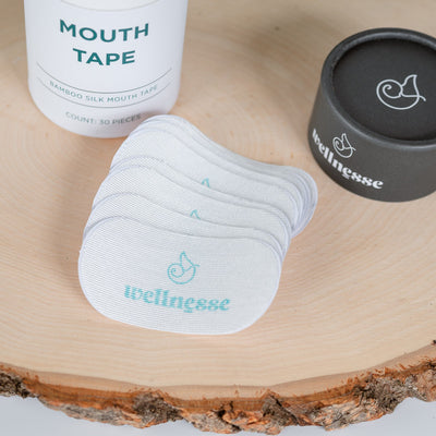 Mouth tape and containers on a wooden surface with 'wellness' branding.