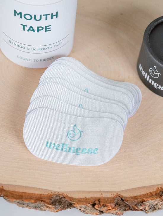 Mouth tape and containers on a wooden surface with 'wellness' branding.