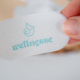 White mouth tape with 'wellnesse' branding held by a hand on a light background