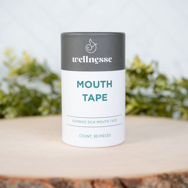 Wellnesse mouth tape container on a wooden surface with a blurred green background