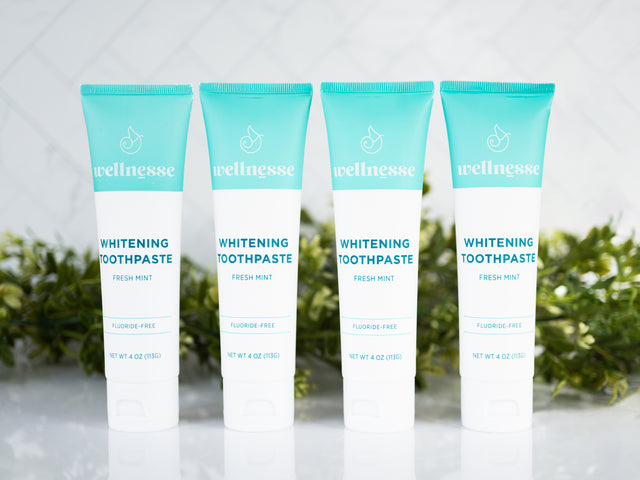 Natural teeth whitening toothpaste in fresh mint flavor, fluoride-free and displayed in a pack of four by Wellnesse.