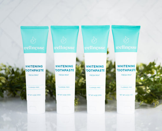 Natural teeth whitening toothpaste in fresh mint flavor, fluoride-free and displayed in a pack of four by Wellnesse.