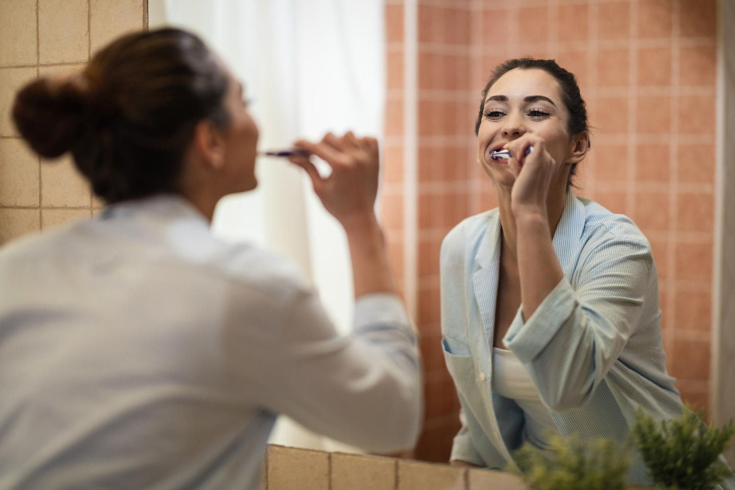 Lady brushing teeth in front of mirror.