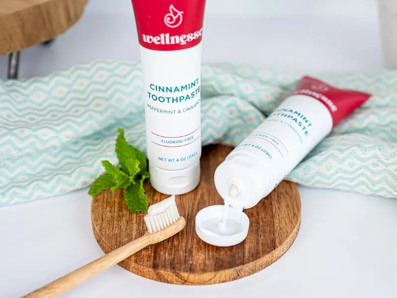 Mineral-based toothpaste with cinnamint flavor shown with a bamboo toothbrush and fresh mint leaves.