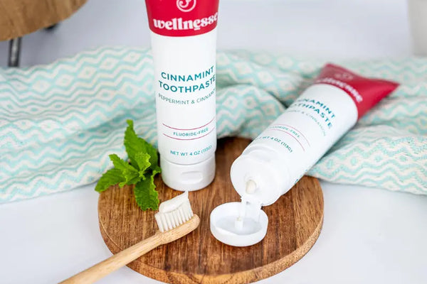 Mineral-based toothpaste with cinnamint flavor shown with a bamboo toothbrush and fresh mint leaves.