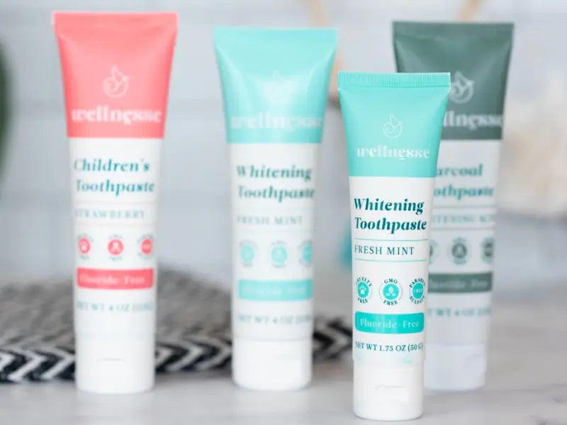 Natural oral care products including fluoride-free toothpaste in fresh mint, charcoal, and strawberry varieties.