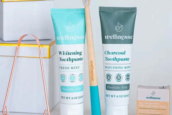 Natural toothpaste set with charcoal and mint options, bamboo toothbrush, floss, and copper tongue scraper.