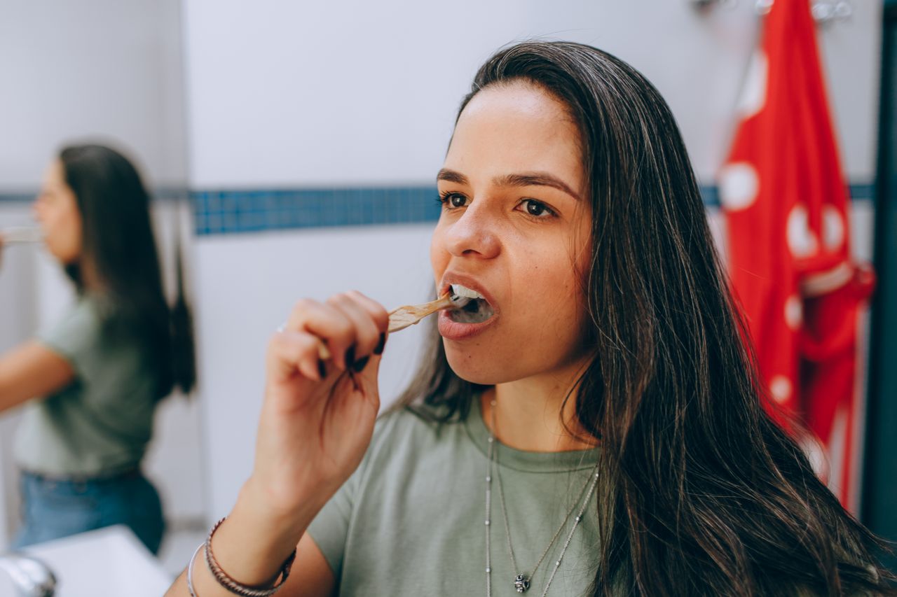 Woman brushing her teeth in a bathroom.