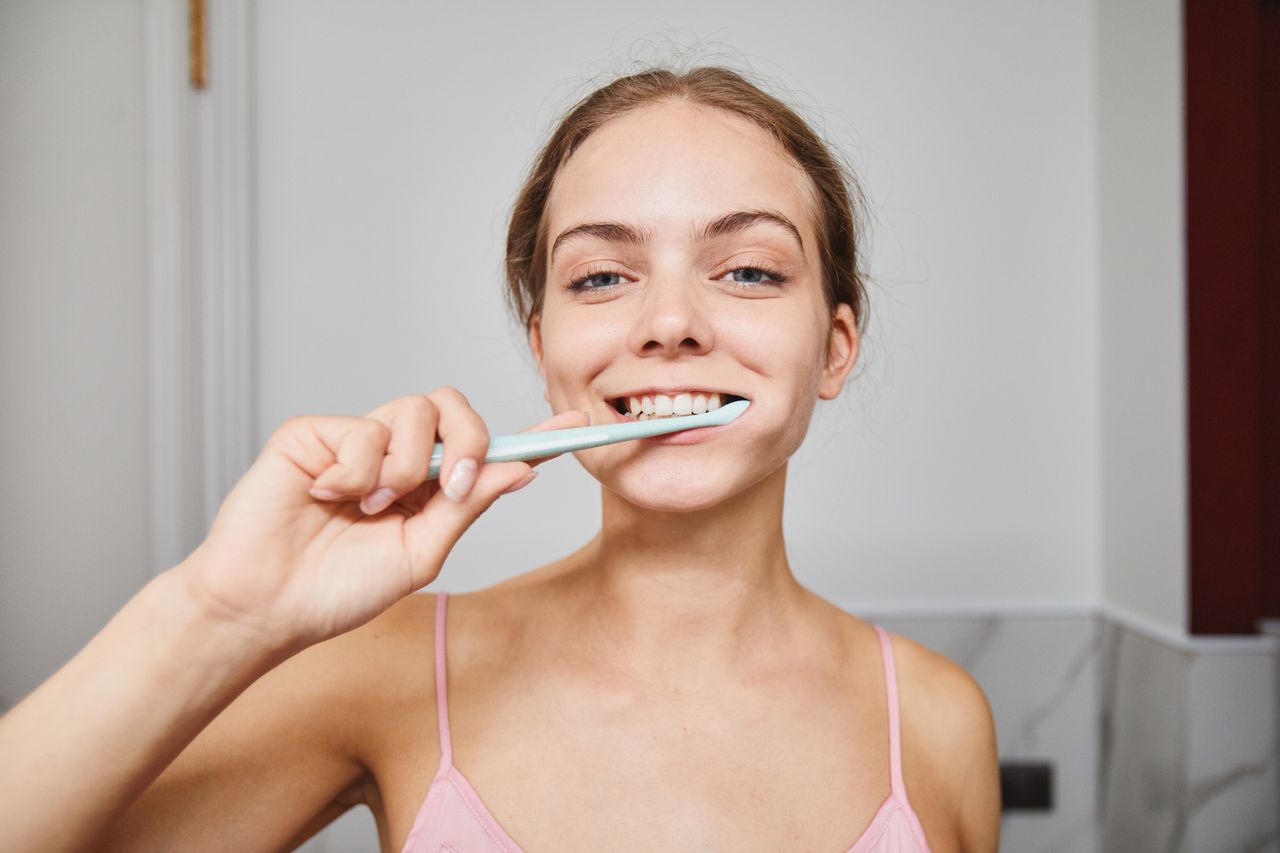 Smiling lady brushing her teeth.