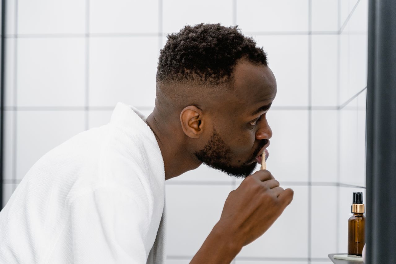 Man brushing teeth in bathroom mirror