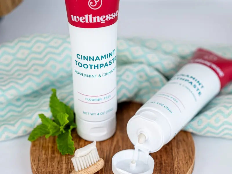 Toothpaste for enamel featuring cinnamint flavor with peppermint and cinnamon beside a small wooden toothbrush.