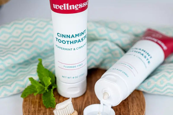 Toothpaste for enamel featuring cinnamint flavor with peppermint and cinnamon beside a small wooden toothbrush.