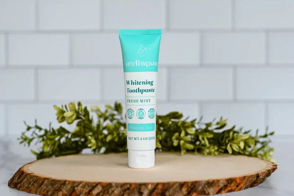 Toothpaste without fluoride displayed on a tree-slice base with decorative greenery in a clean bathroom setting
