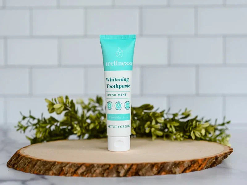 Toothpaste without fluoride displayed on a tree-slice base with decorative greenery in a clean bathroom setting