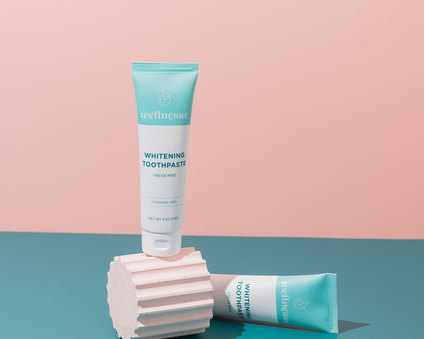 Woman smiling while brushing with the best hydroxyapatite toothpaste by Wellnesse