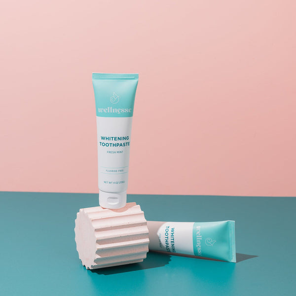 Woman smiling while brushing with the best hydroxyapatite toothpaste by Wellnesse