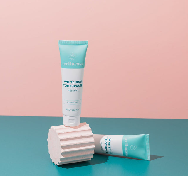 Woman smiling while brushing with the best hydroxyapatite toothpaste by Wellnesse