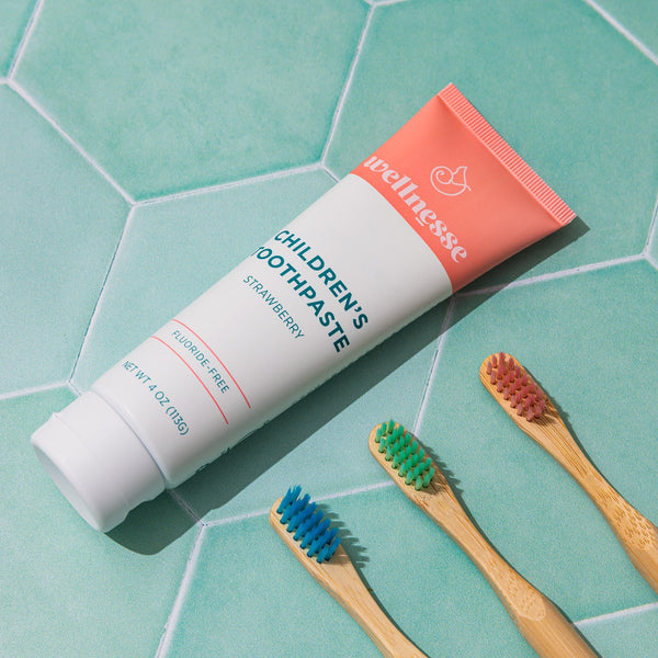 Child brushing teeth with Wellnesse strawberry toothpaste and a bamboo toothbrush