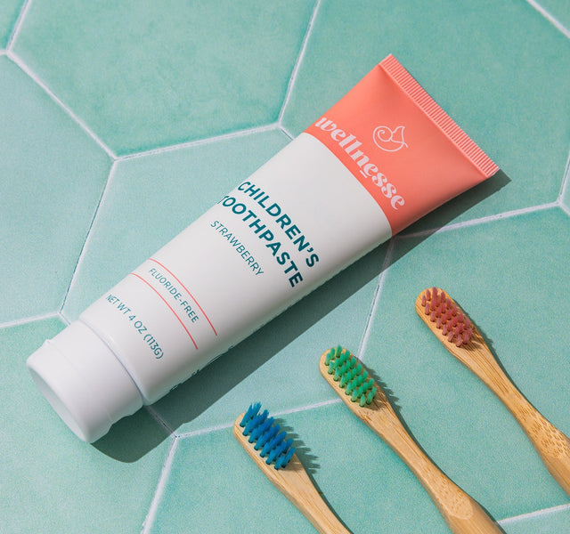 Child brushing teeth with Wellnesse strawberry toothpaste and a bamboo toothbrush