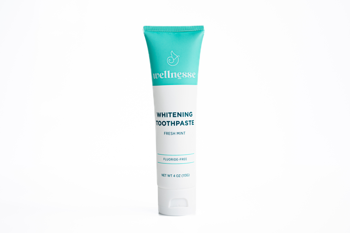 Organic whitening toothpaste in a Wellnesse tube with fluoride-free fresh mint formula, featuring a teal cap and clean white background.