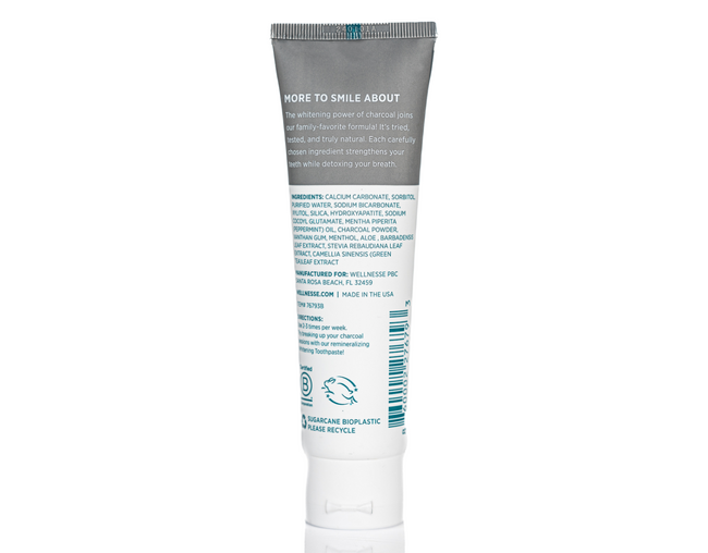 Charcoal hydroxyapatite natural toothpaste with detoxifying ingredients and full ingredient list shown on back of fluoride-free Wellnesse tube