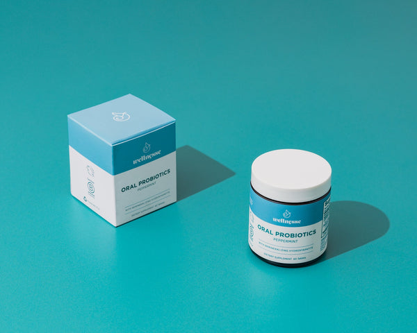 Wellnesse oral probiotic mints scattered beside the open jar showing the dissolvable tablet shape