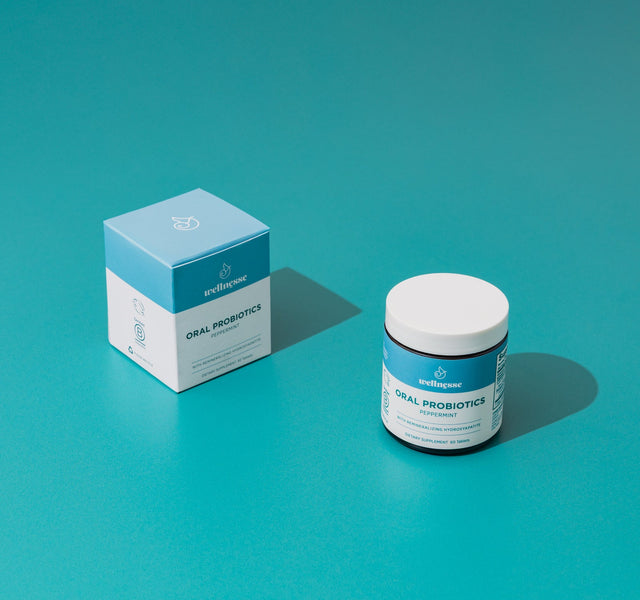 Wellnesse oral probiotic mints scattered beside the open jar showing the dissolvable tablet shape