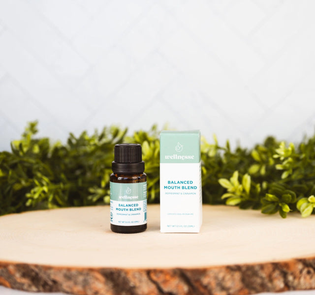 Wellnesse non toxic mouthwash bottle and box in peppermint and cinnamon blend on wood with greenery