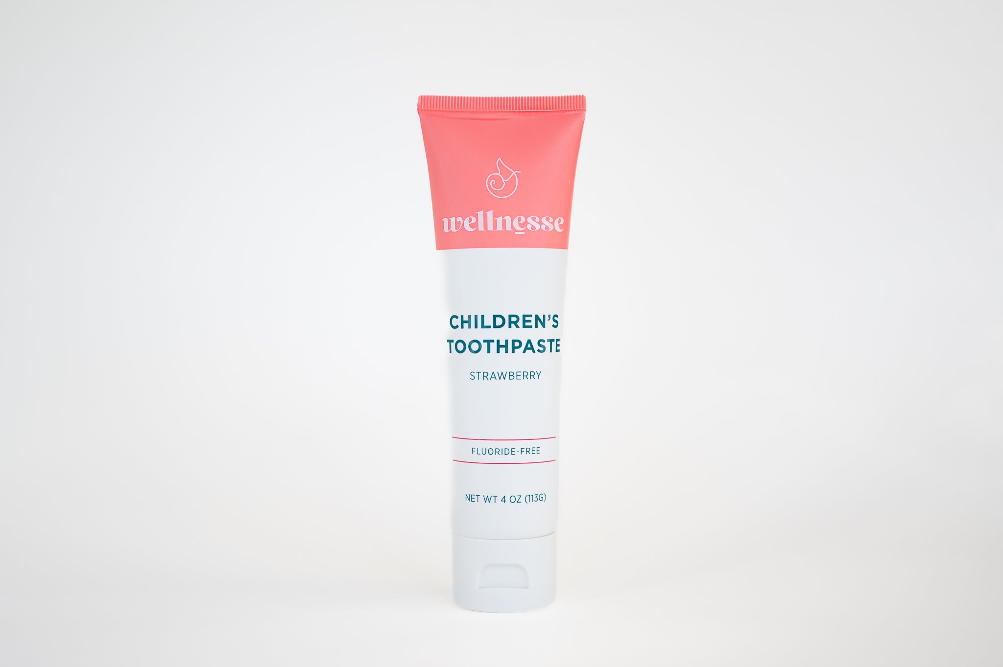 Strawberry fluoride free toothpaste for sensitive teeth in a children's Wellnesse tube with clean design on white background