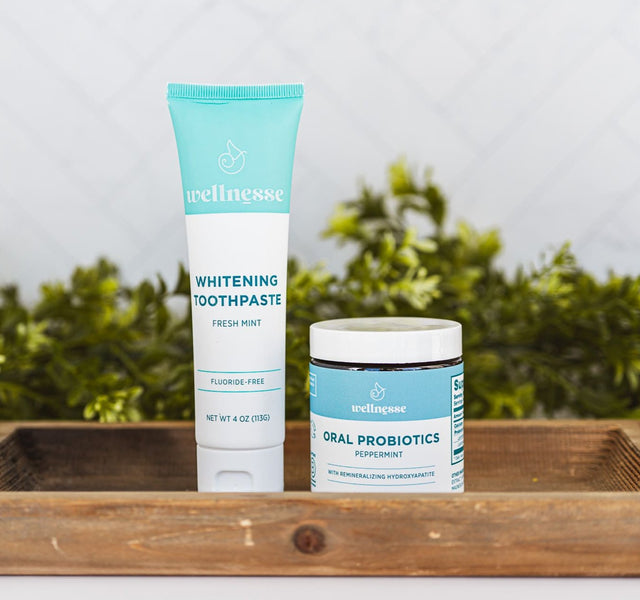 Wellnesse remineralizing toothpaste and oral probiotic set displayed on a natural wood surface