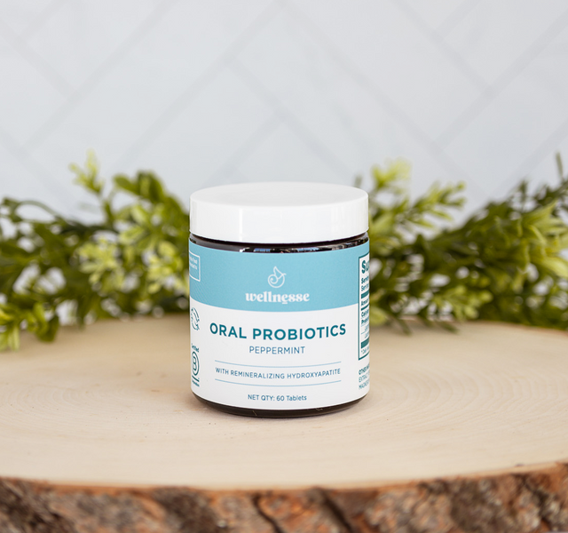 Wellnesse oral probiotic mints jar with remineralizing hydroxyapatite on a natural wood slice