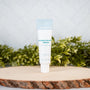 Wellnesse hydroxyapatite serum fluoride-free tube on a natural wood slice with green foliage backdrop