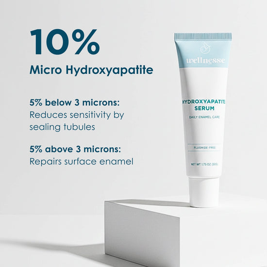 Wellnesse Hydroxyapatite Serum tube with 10% micro hydroxyapatite for daily enamel care displayed on a white pedestal.