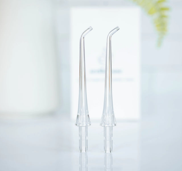 Wellnesse water flosser replacement tips shown as two clear curved nozzles on a white surface