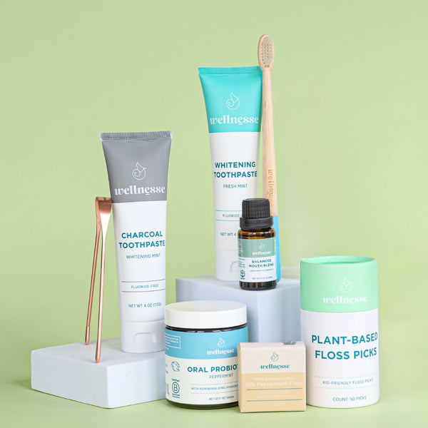 Full layout of the Wellnesse oral care kit with toothpaste, probiotics, floss picks, and tongue scraper