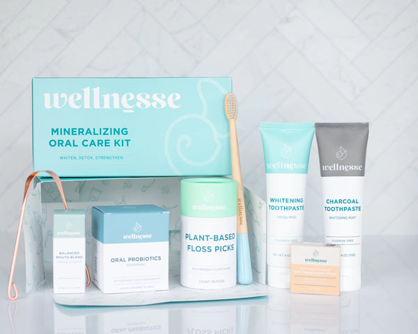 Dental clean kit by Wellnesse featuring toothpaste, floss picks, probiotics, copper tongue scraper, and bamboo toothbrush for oral health