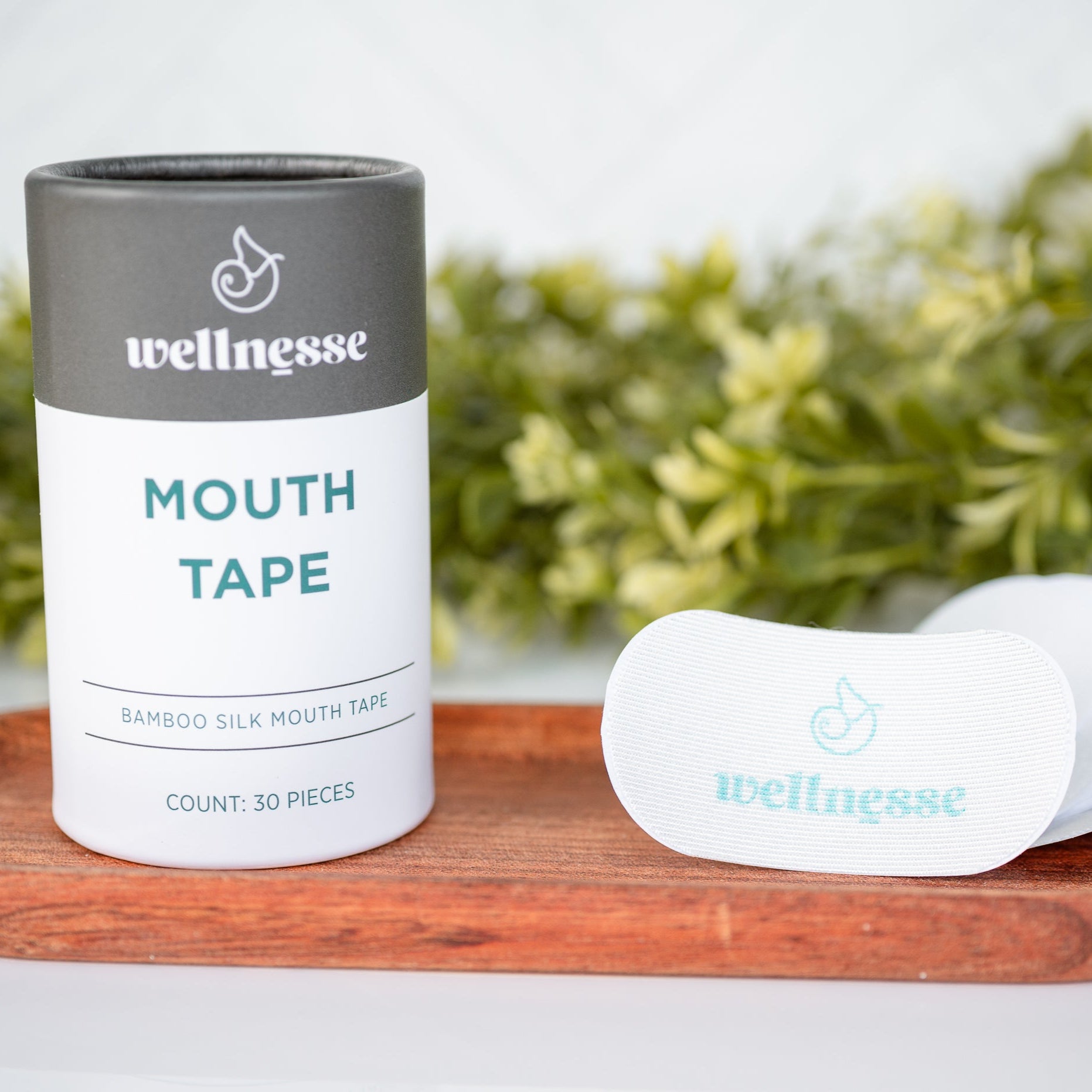 Wellnesse mouth tape packaging on a wooden tray with a white background