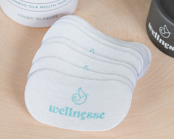 Mouth tape and containers on a wooden surface with 'wellness' branding.