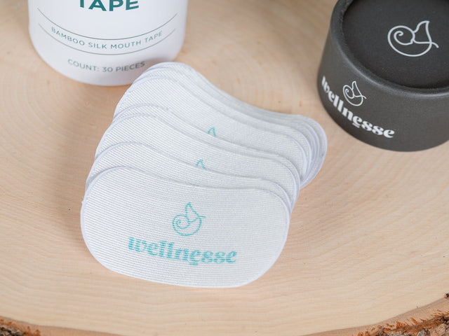 Mouth tape and containers on a wooden surface with 'wellness' branding.