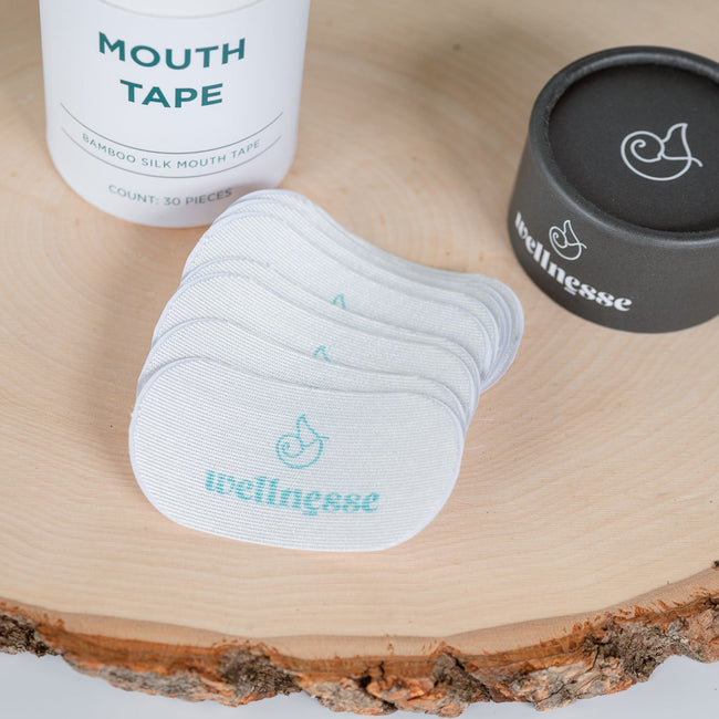 Mouth tape and containers on a wooden surface with 'wellness' branding.