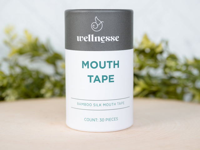 Wellnesse mouth tape container on a wooden surface with a blurred green background