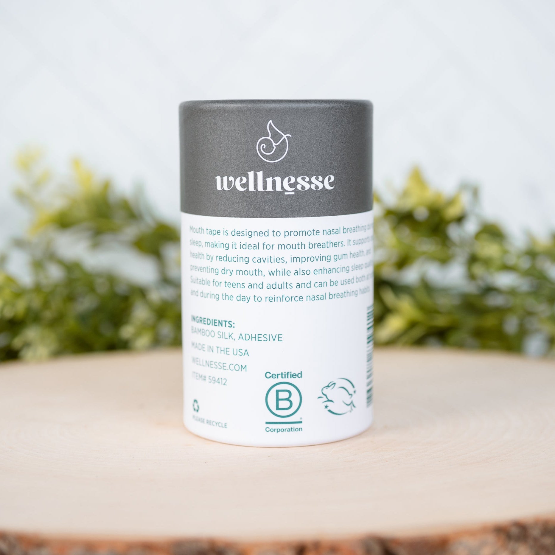 Wellnesse product container on a wooden surface with greenery in the background