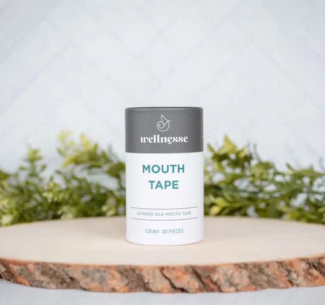 Wellnesse non toxic mouth tape 30-piece bamboo silk container on a natural wood slice with greenery