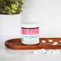 Oral probiotics in raspberry lemonade flavor by Wellnesse, with white tablets scattered on a wooden tray.